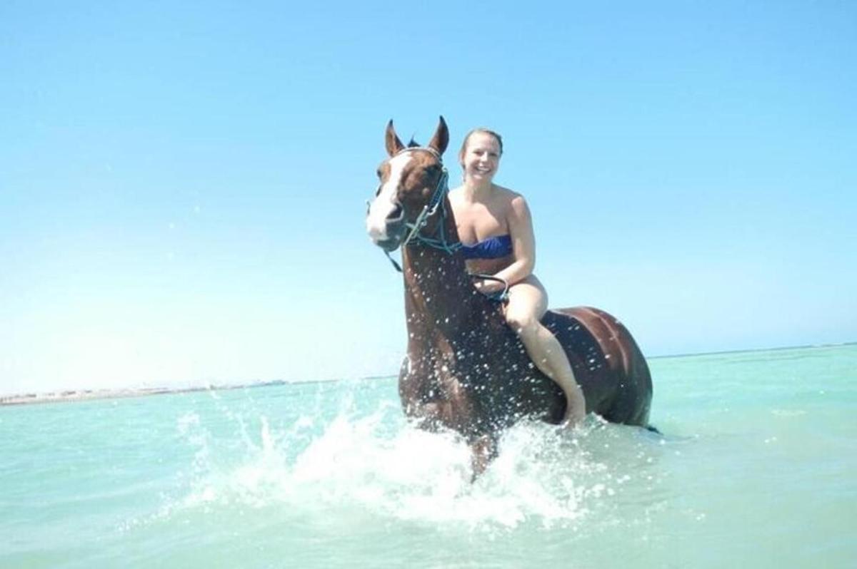 una dona en bikini muntant a cavall a l'oceà