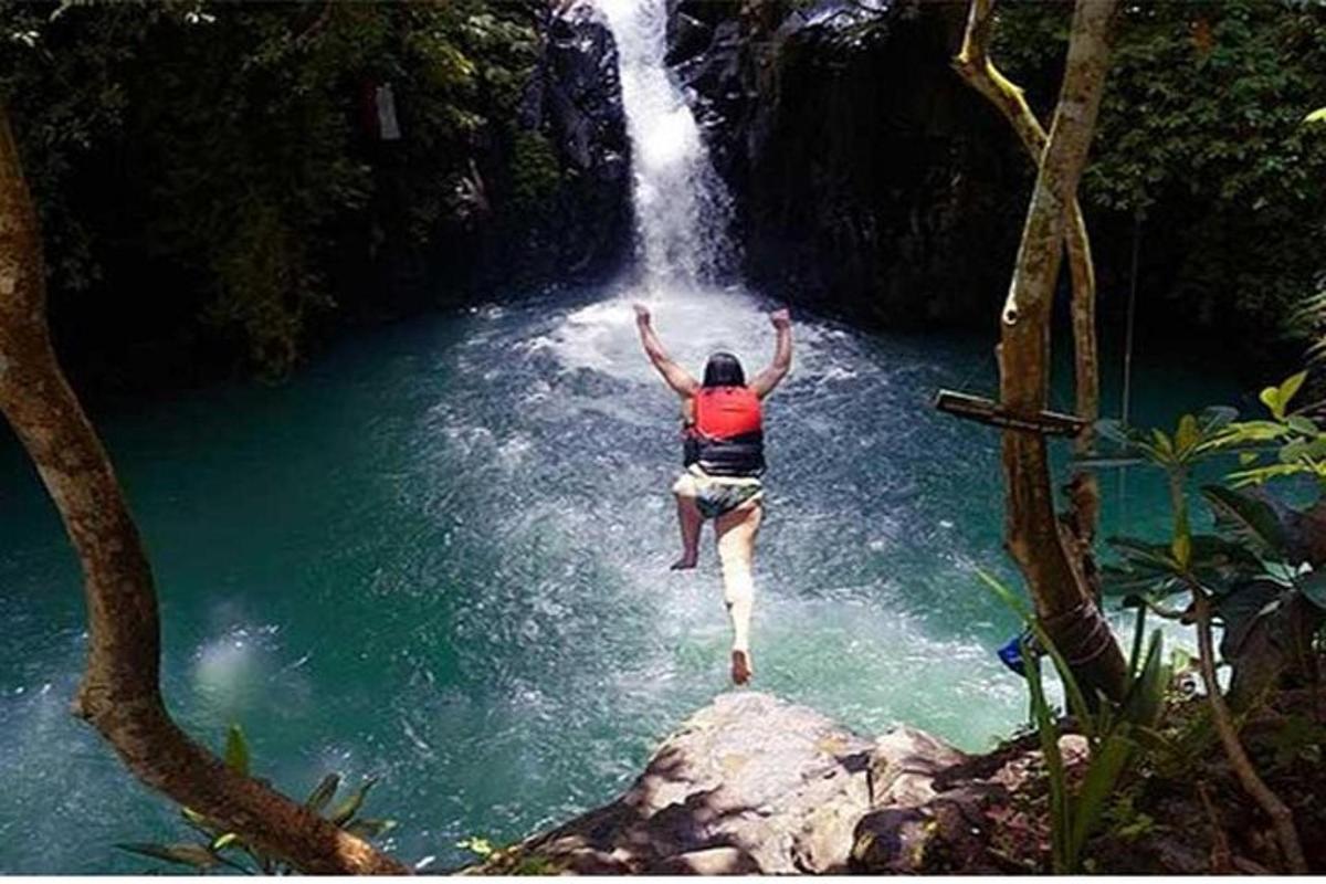 isang taong tumatalon mula sa isang talon patungo sa isang anyong tubig