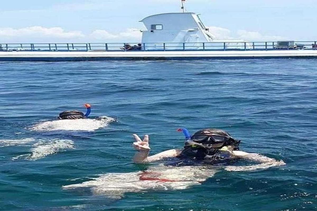 dos personas en el agua junto a un barco