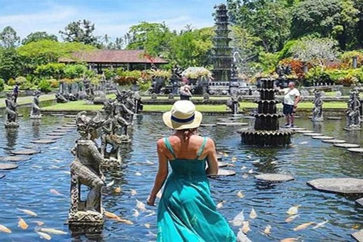 Una mujer con un vestido azul parada en una fuente.