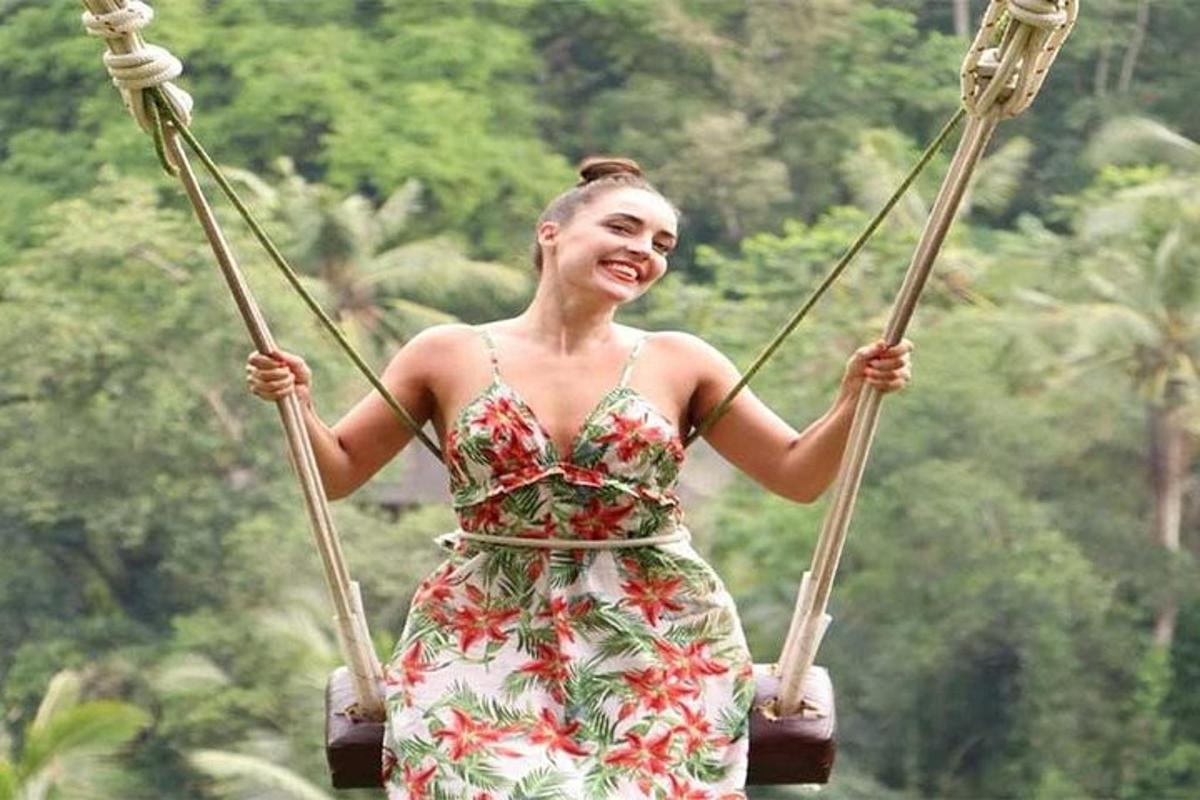 a woman in a dress riding on a swing
