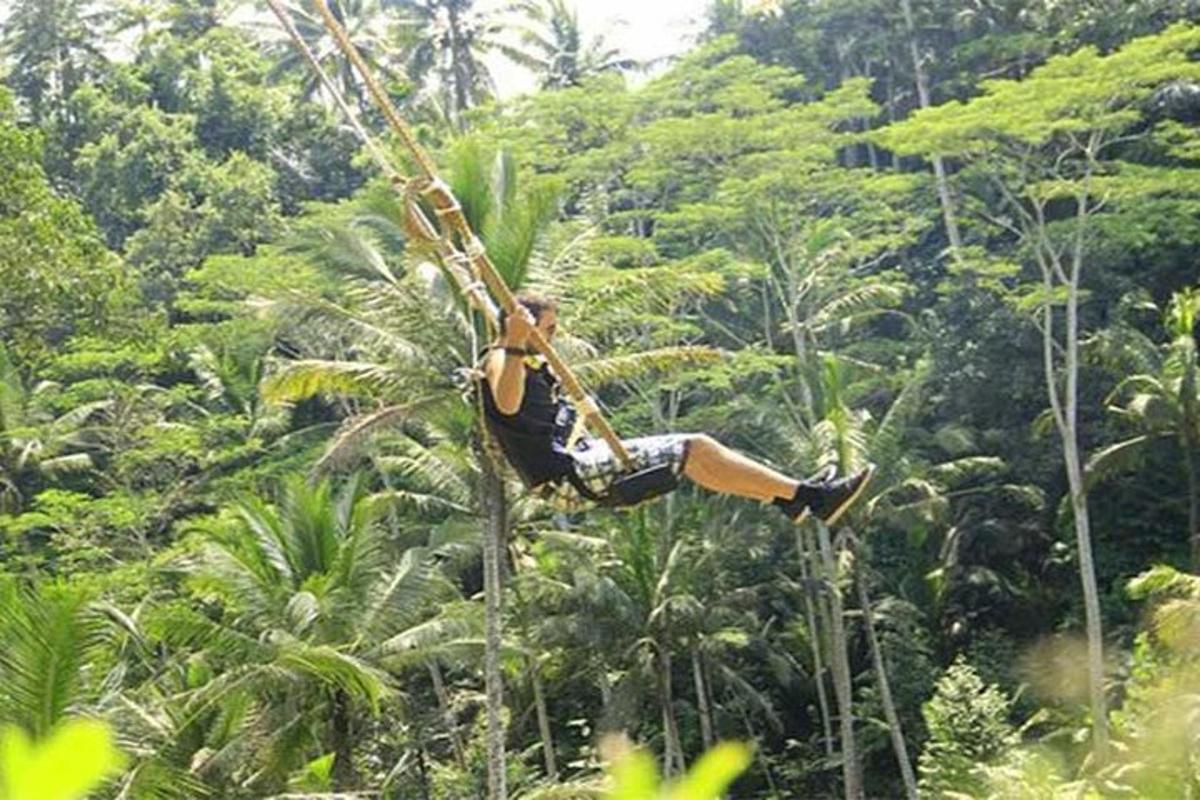 een man die aan een touw in de jungle slingert