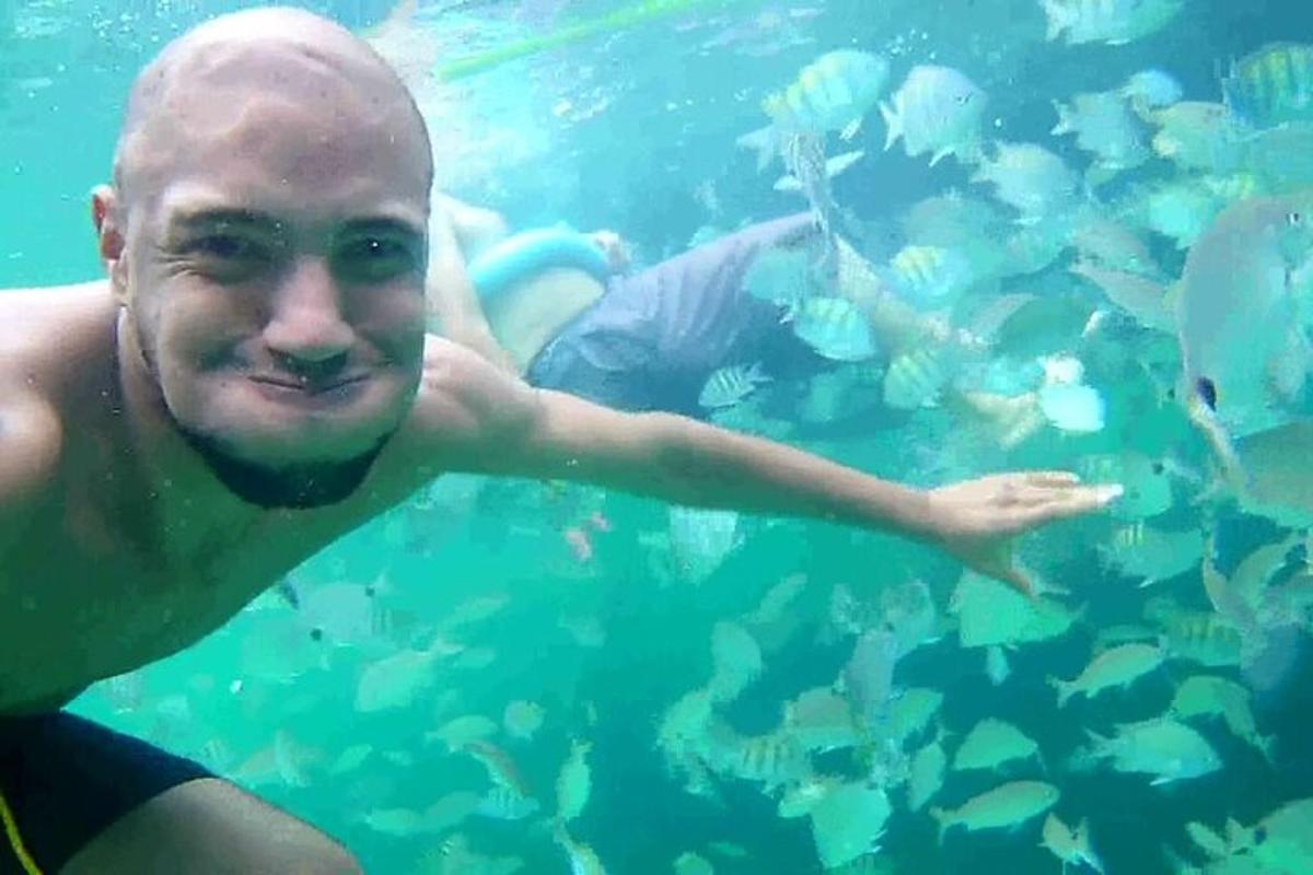 a man swimming in the water near a school of fish