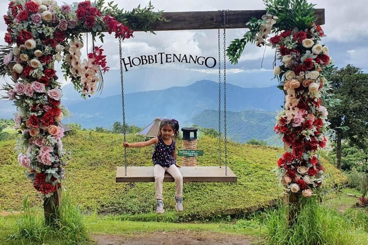 a little girl sitting on a swing with flowers