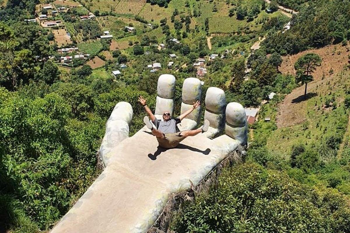 a man is laying on top of a giant hand