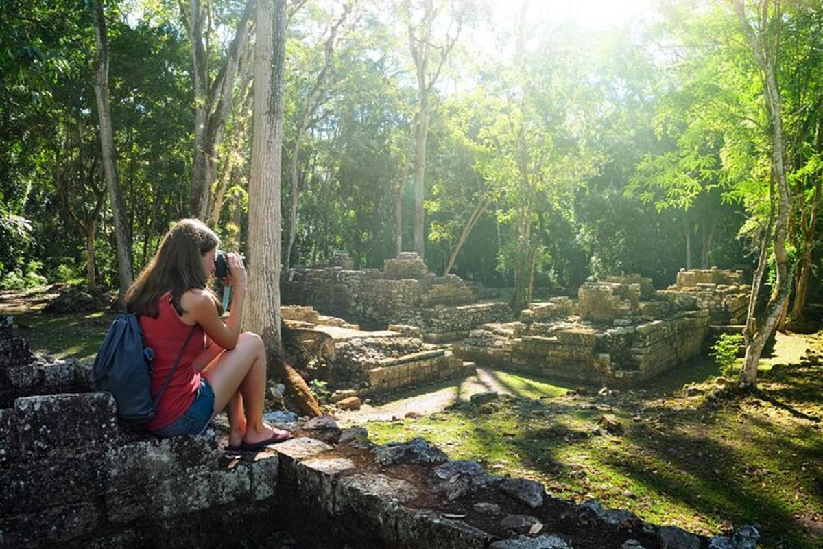 a woman sitting on a wall taking a picture of ruins