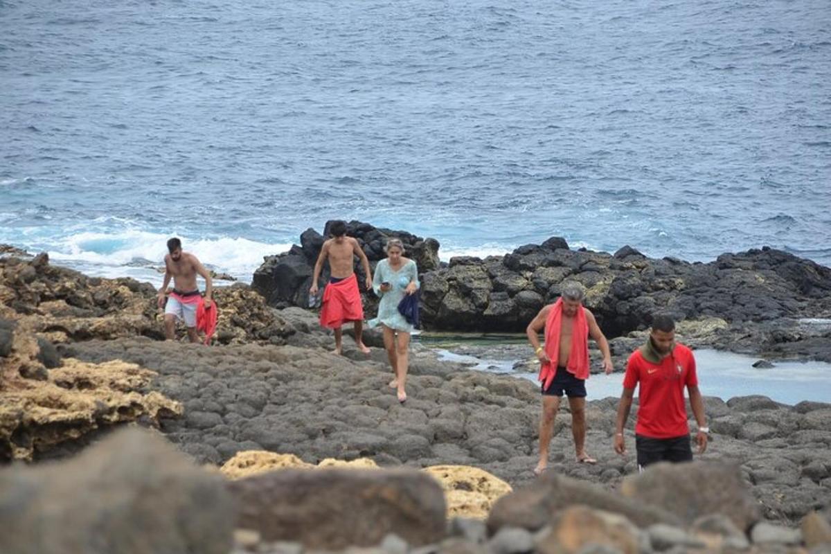 a group of people walking on rocks on the beach