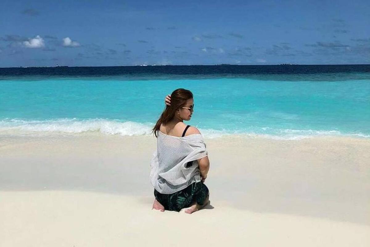 una donna seduta sulla sabbia della spiaggia