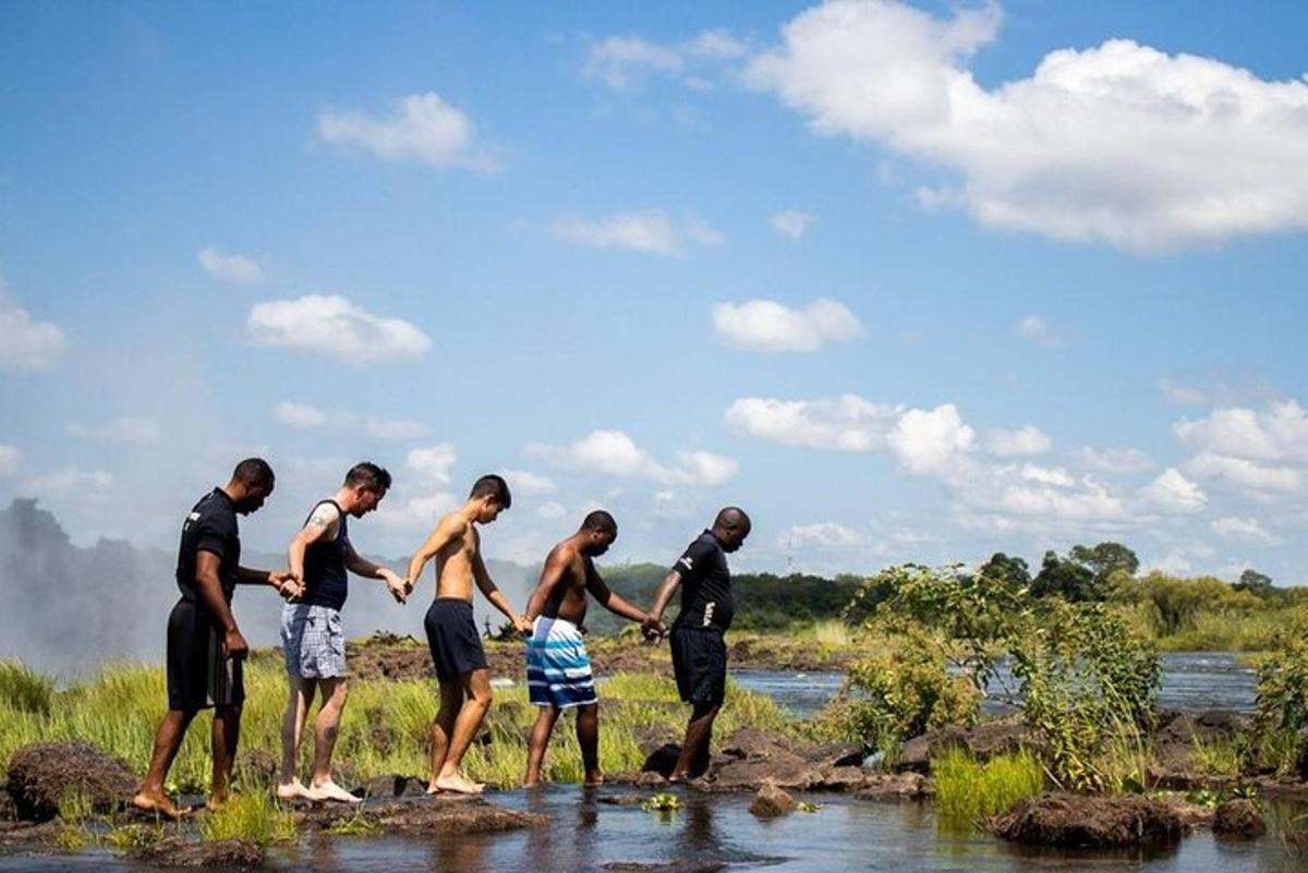 a group of men standing on rocks near a river
