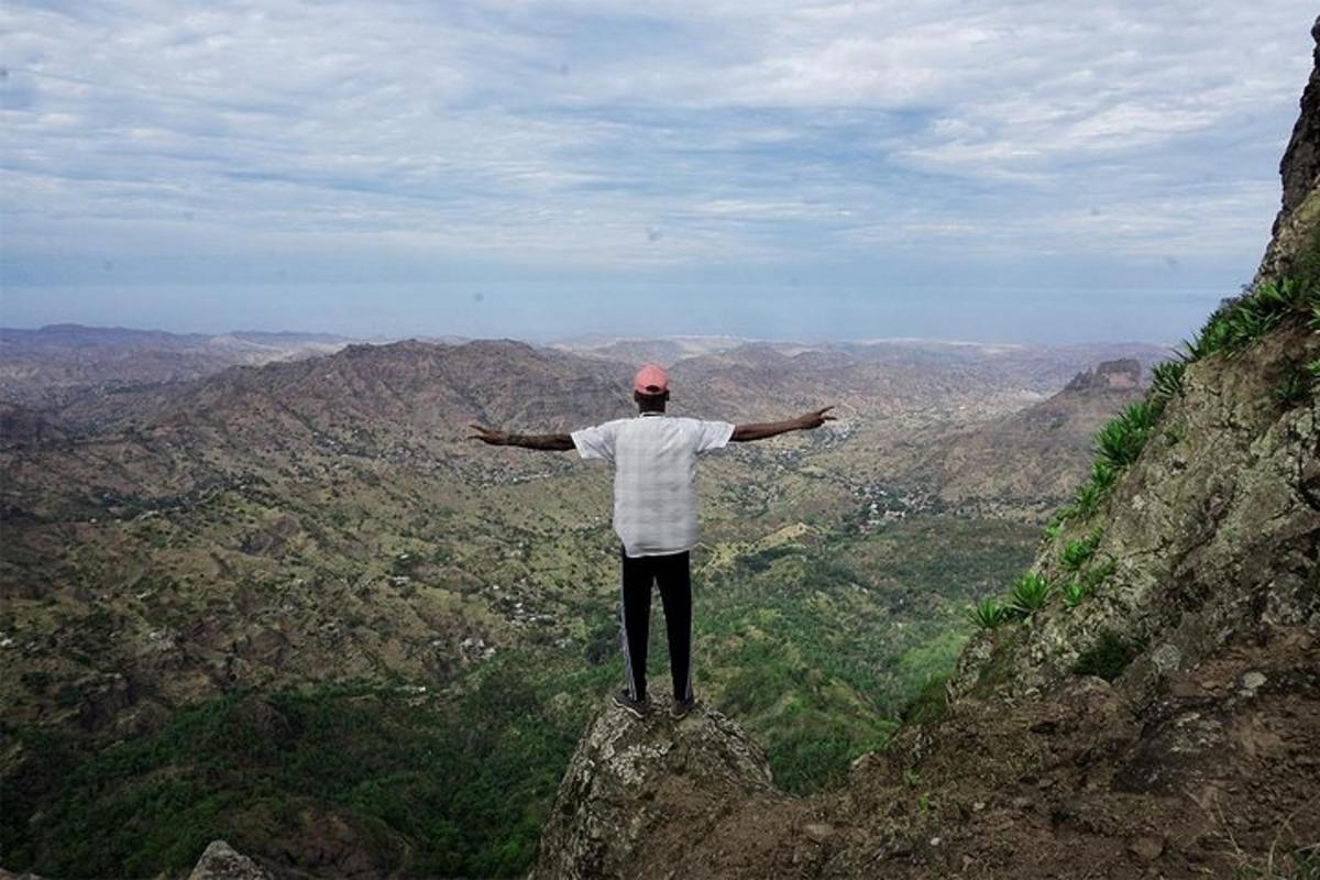 a man standing on top of a mountain with his arms out
