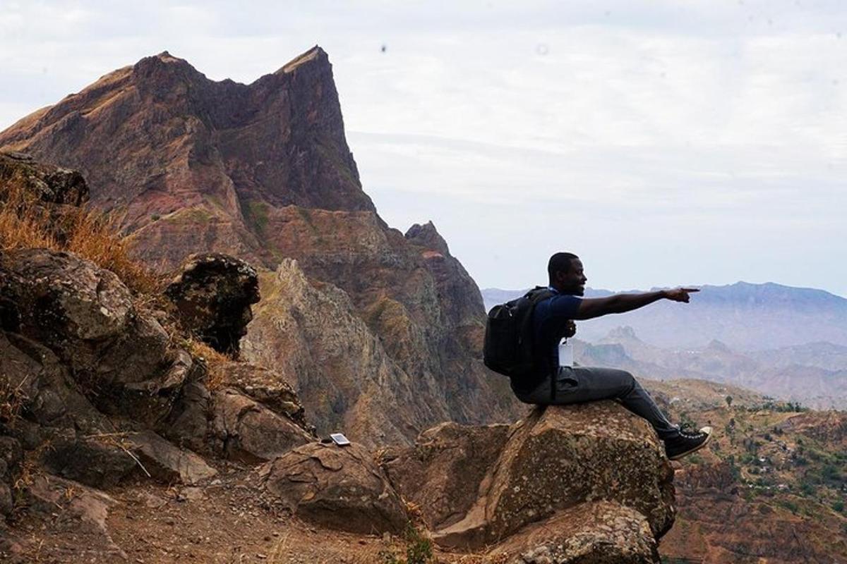 a man sitting on a rock pointing at a mountain