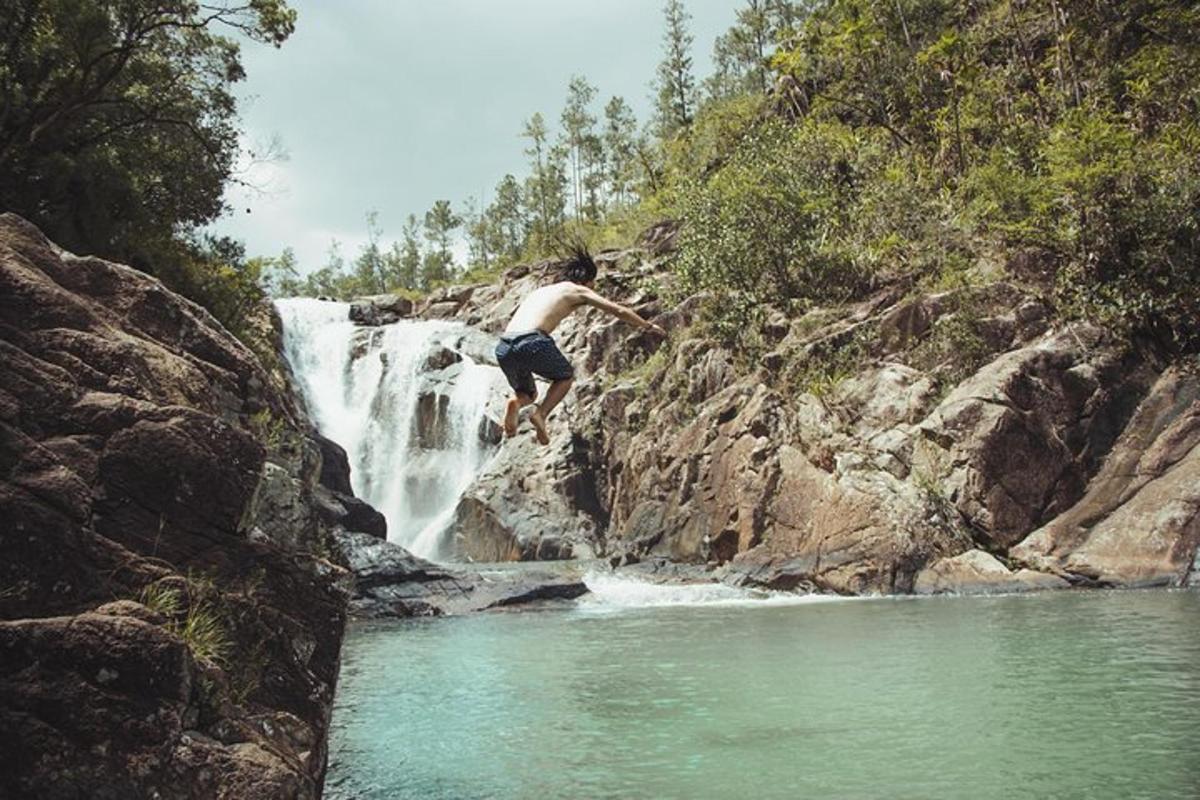 a man jumping off a waterfall into a river