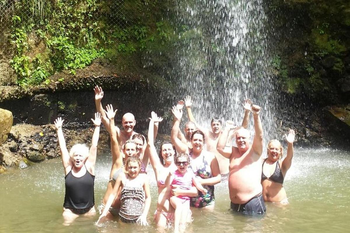 a group of people in the water in front of a waterfall