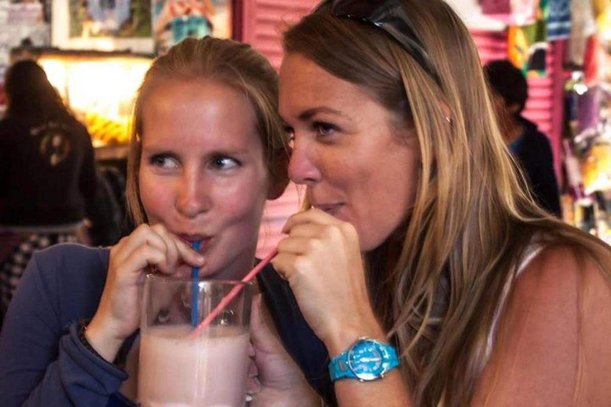 two women sitting at a table drinking a drink