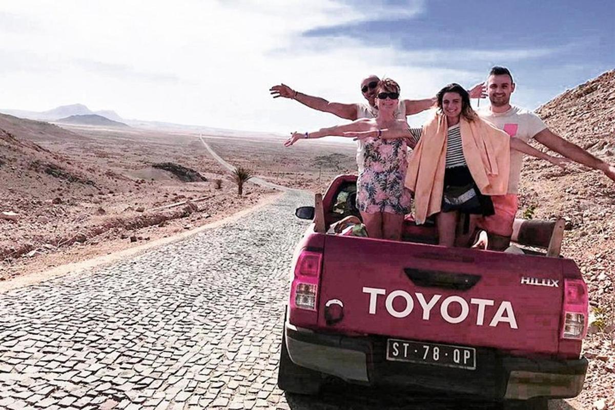 three people sitting in the back of a car on a road