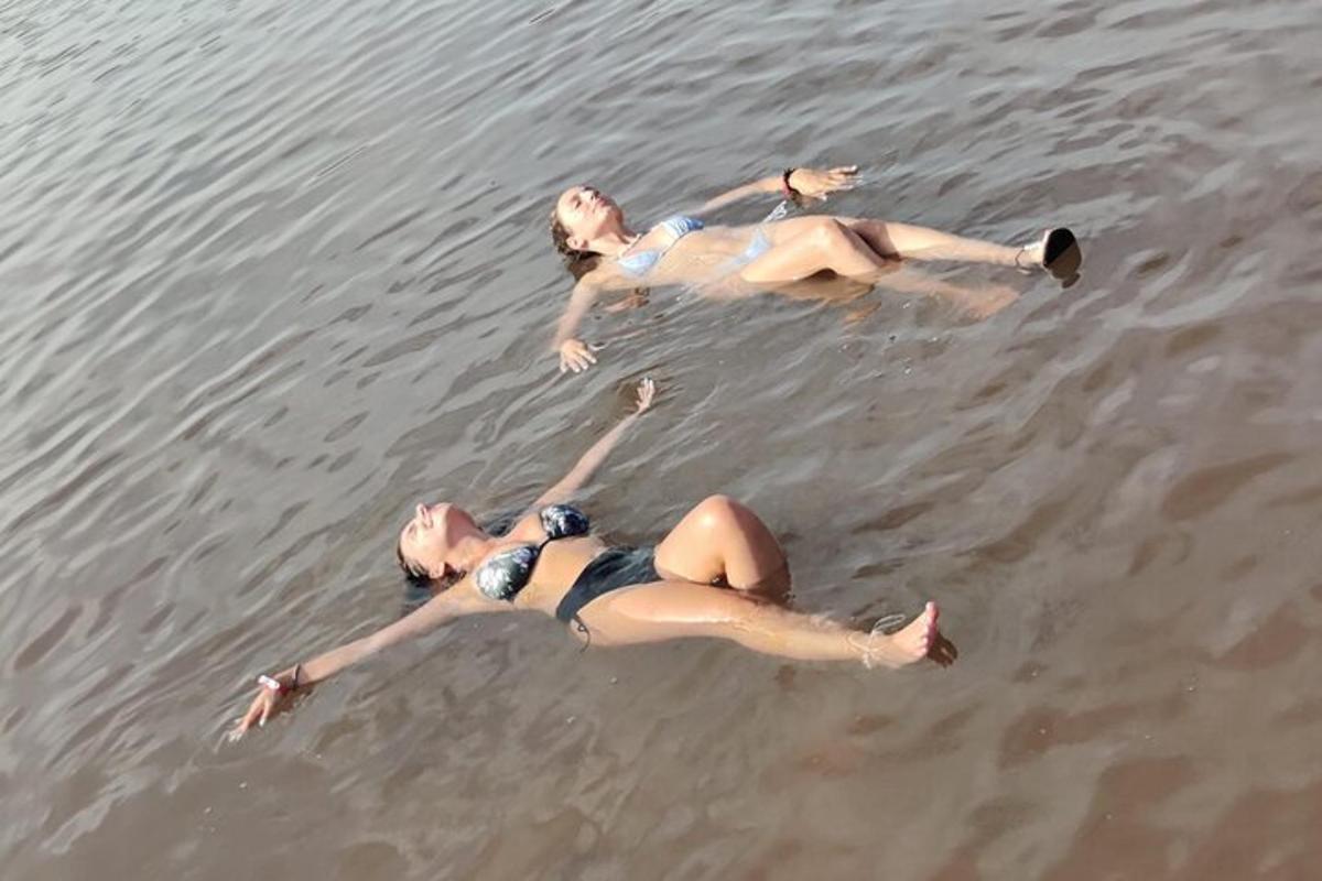 two women laying in the water on the beach