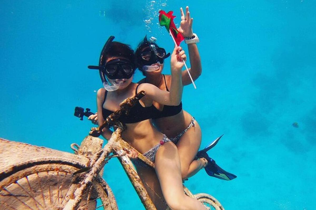 two women in bathing suits sitting on a bike in the water