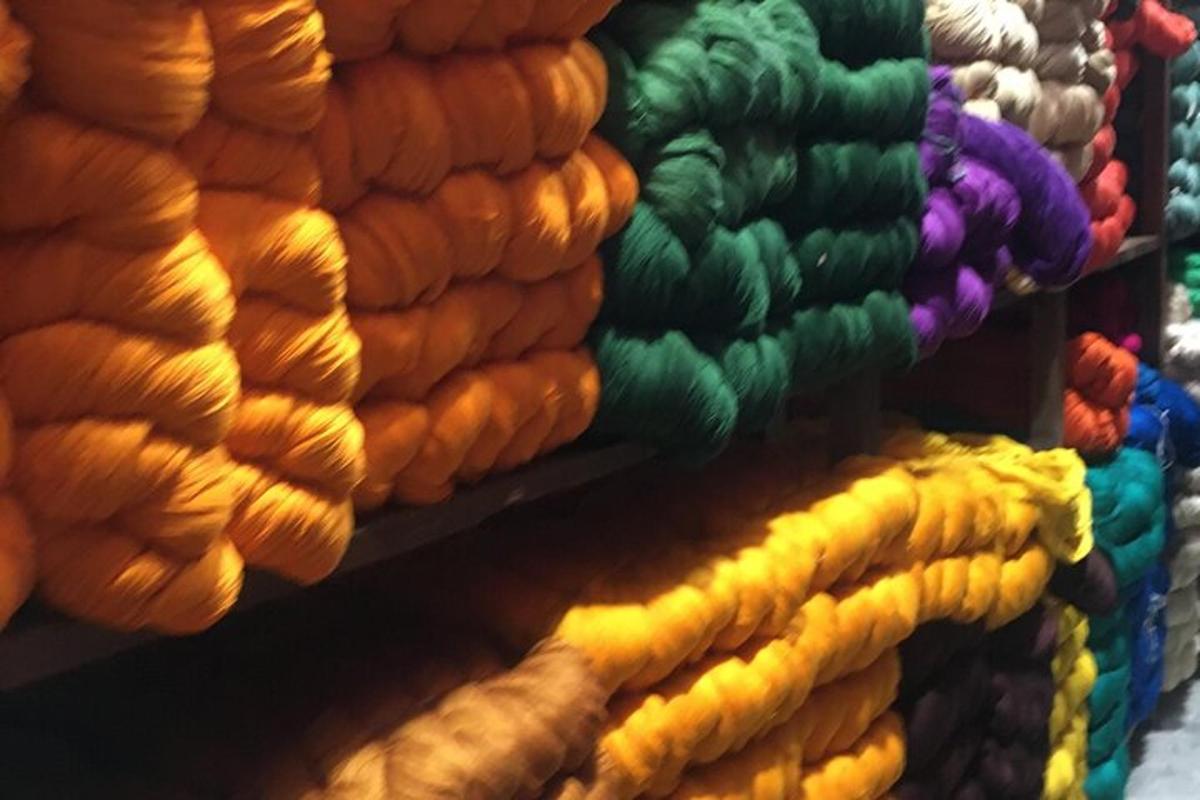 a wall of colored yarns on a shelf
