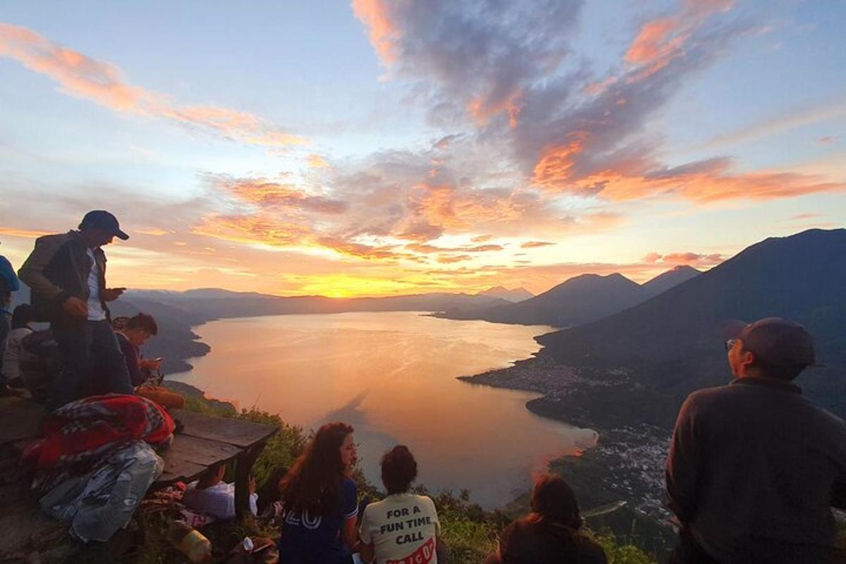 a group of people sitting on a bench watching the sunset