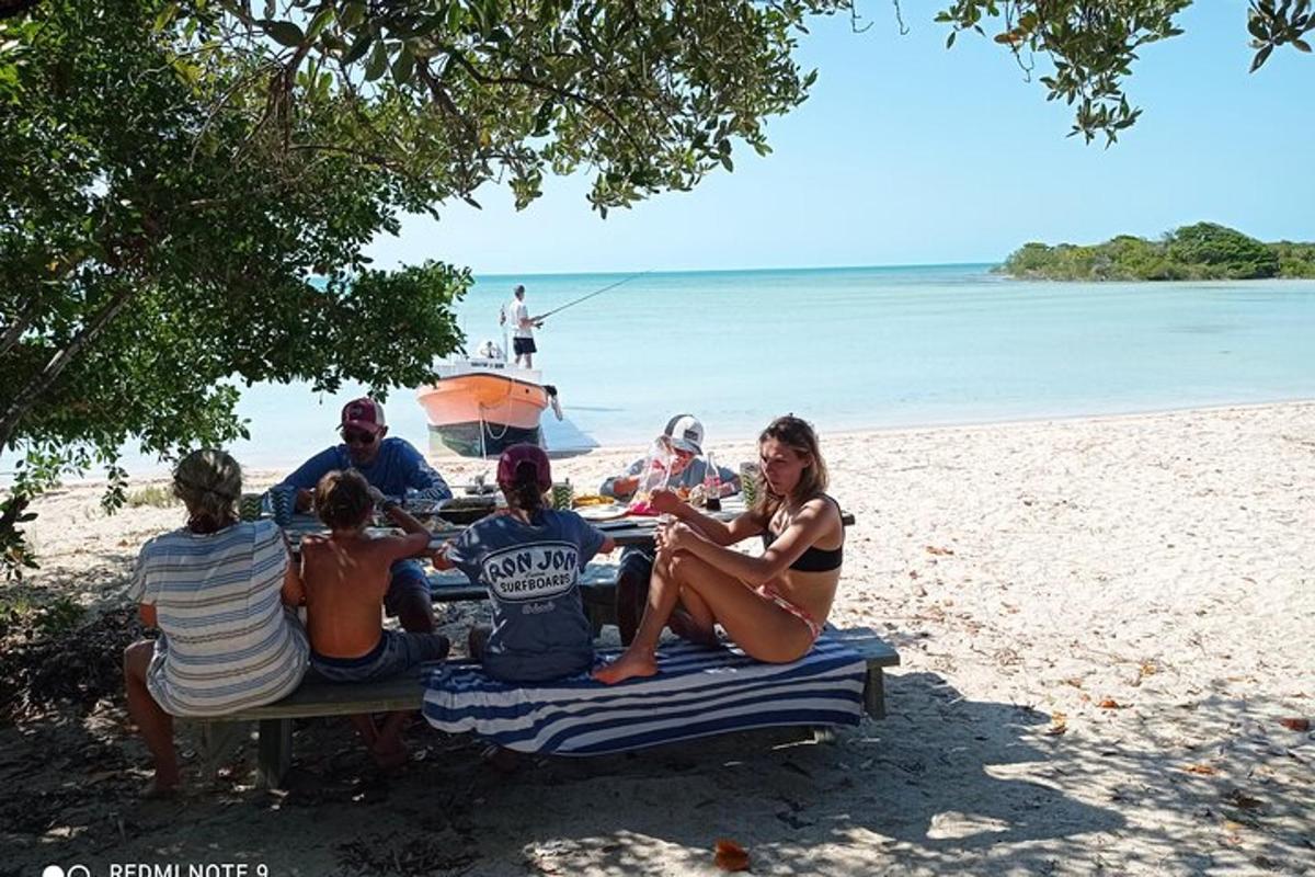 a group of people sitting at a picnic table on the beach