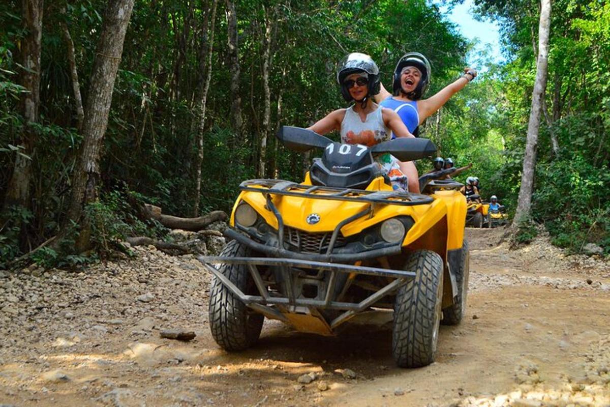 hai người đi trên một chiếc xe bốn bánh trên một con đường đất