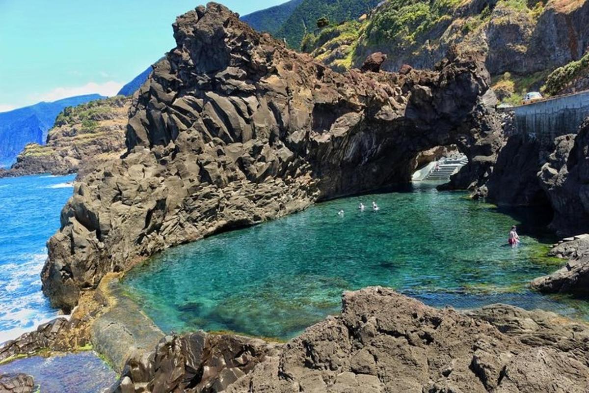 skupina ljudi, ki plavajo v bazenu na skalnati plaži