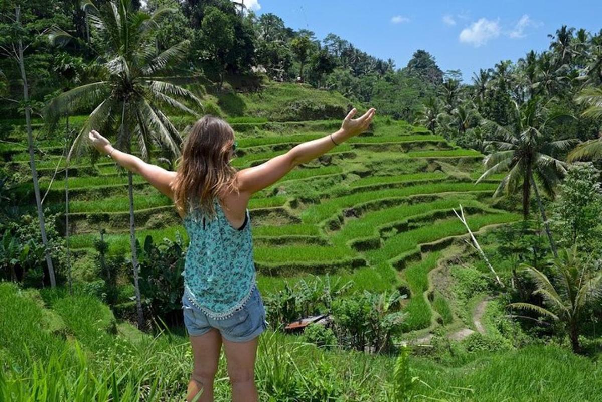 Una mujer parada en una colina mirando un campo de arroz.