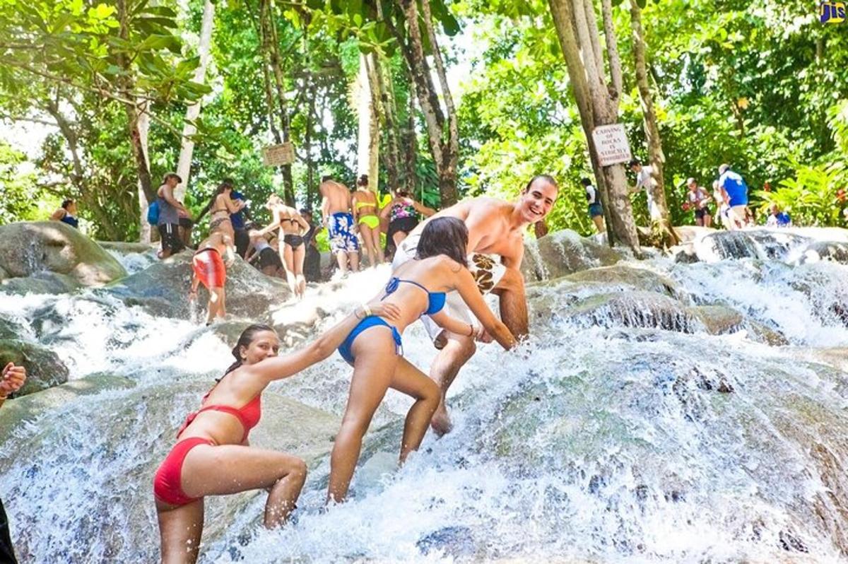 група људи који се играју у води код водопада
