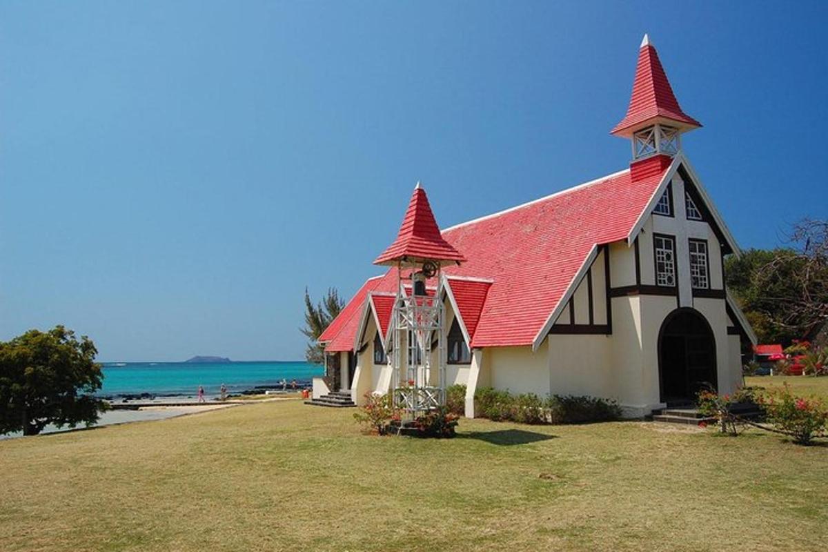 uma igreja com telhado vermelho com o oceano ao fundo
