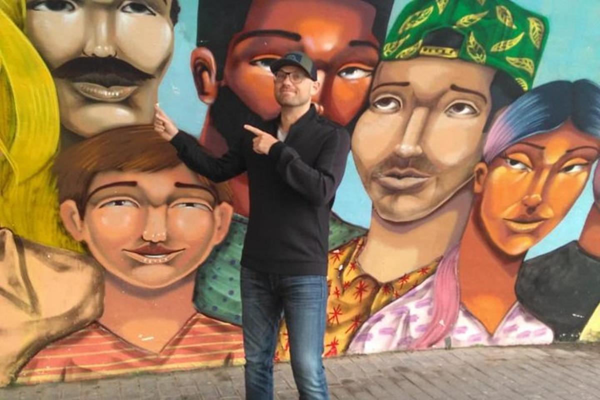Un hombre parado frente a un mural