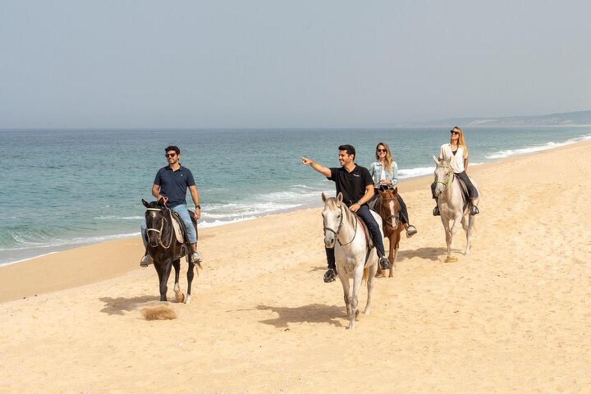 un grupo de personas montando a caballo en la playa