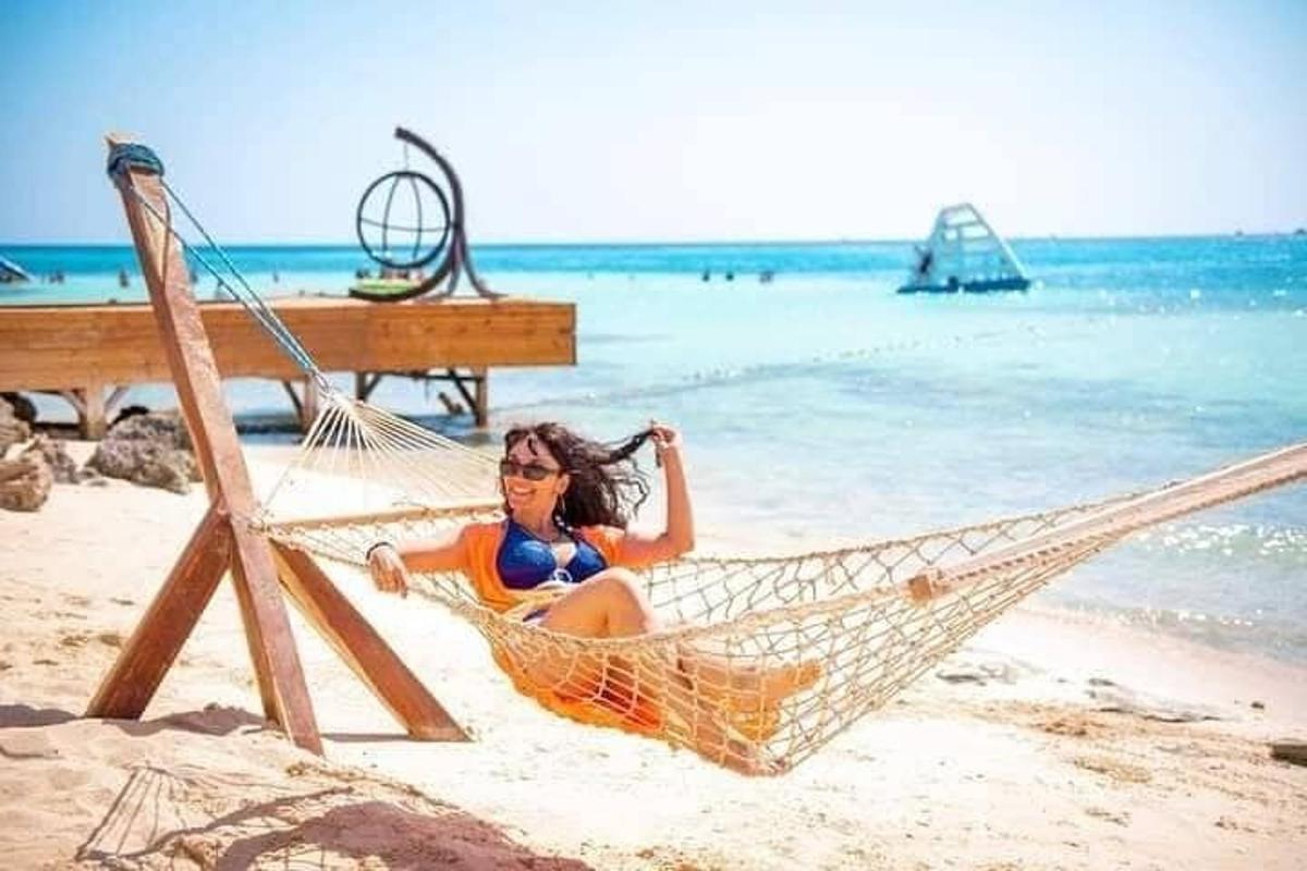 a woman sitting in a hammock on the beach
