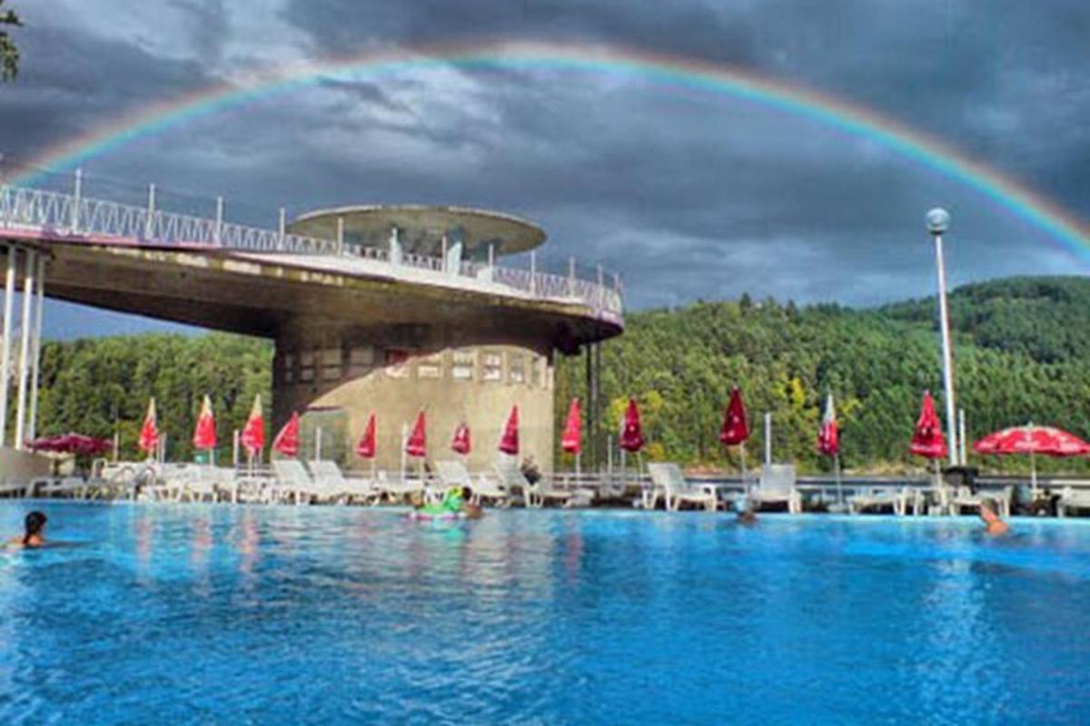 un arcobaleno sopra una piscina con un ponte