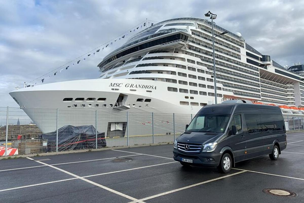 a van parked in a parking lot in front of a cruise ship