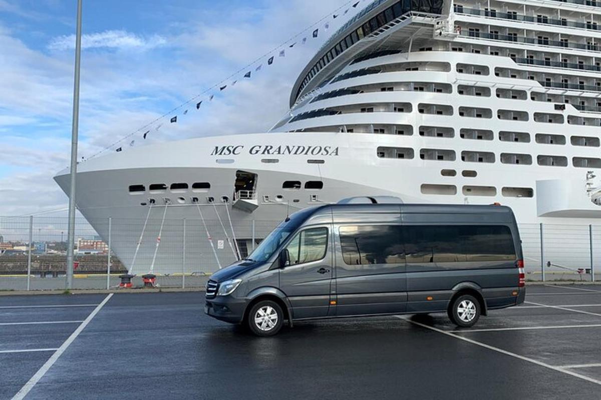 a van parked in a parking lot in front of a cruise ship