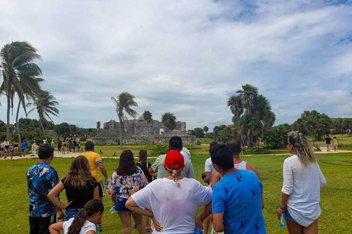 a group of people standing in a field looking at a kite