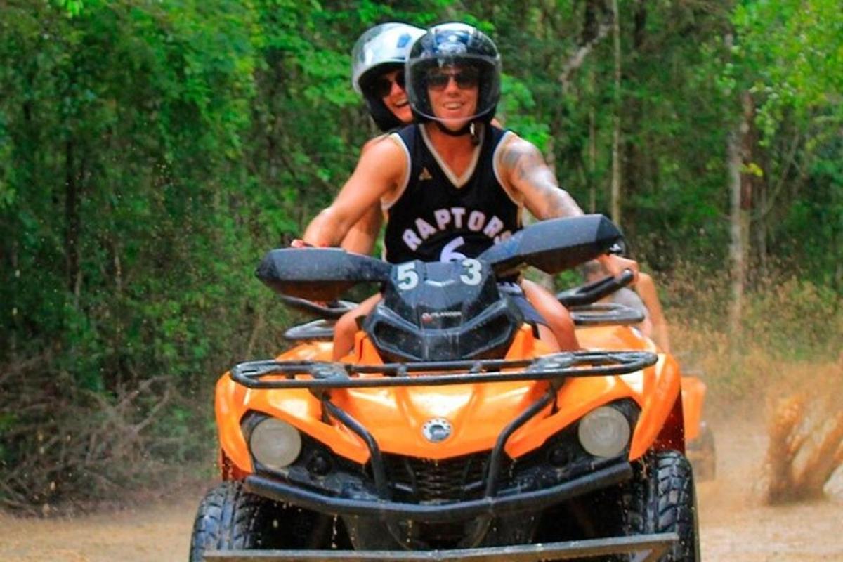 Két ember egy narancssárga ATV-n halad egy földúton