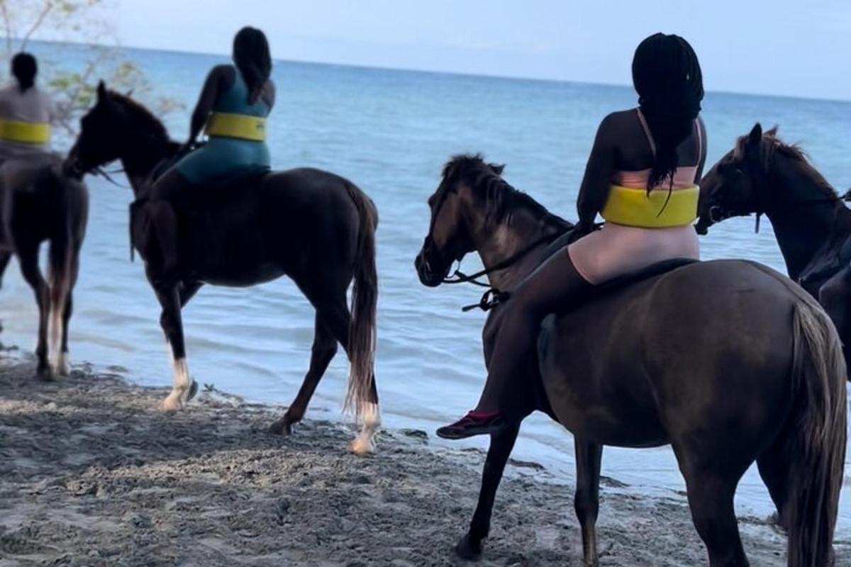 a group of people riding horses on the beach