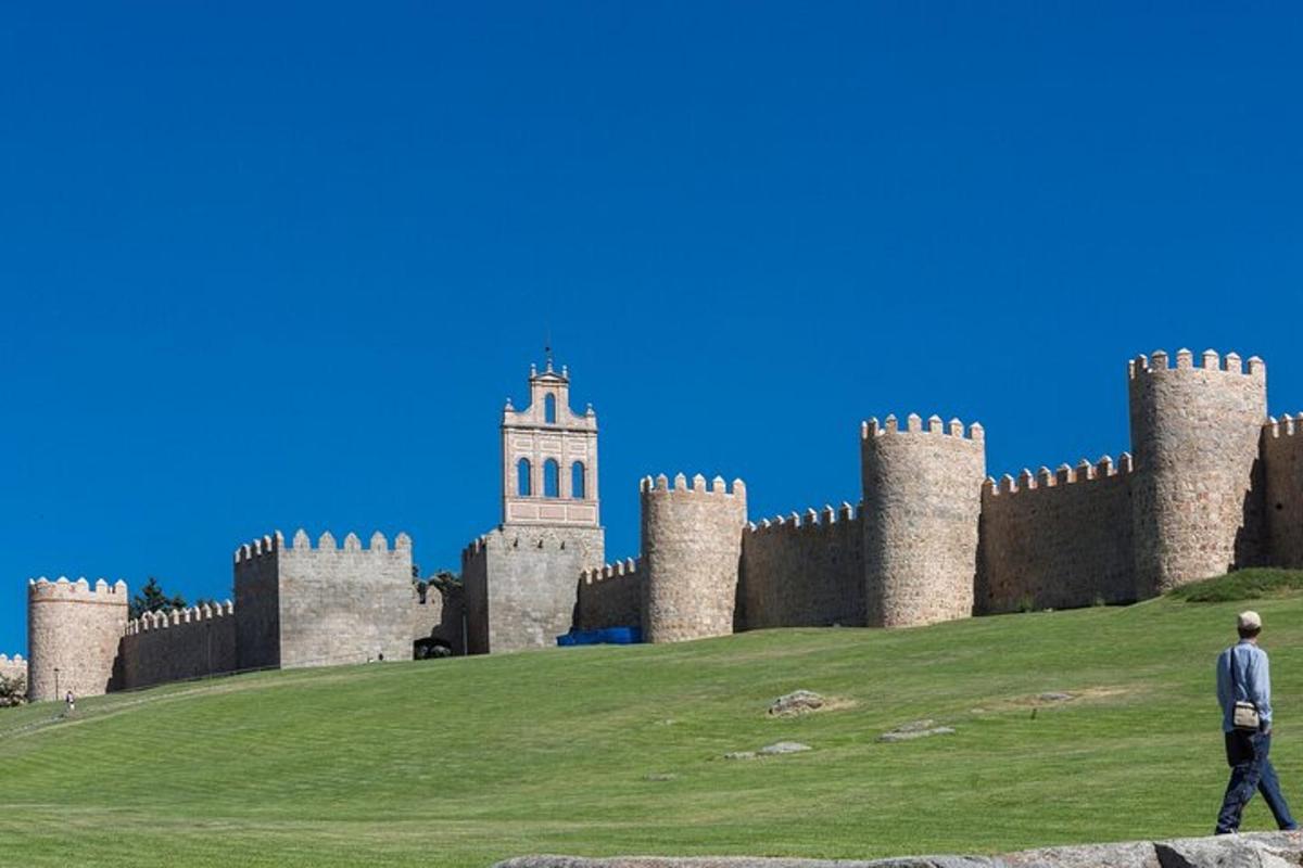 un home caminant davant d'un castell amb una torre
