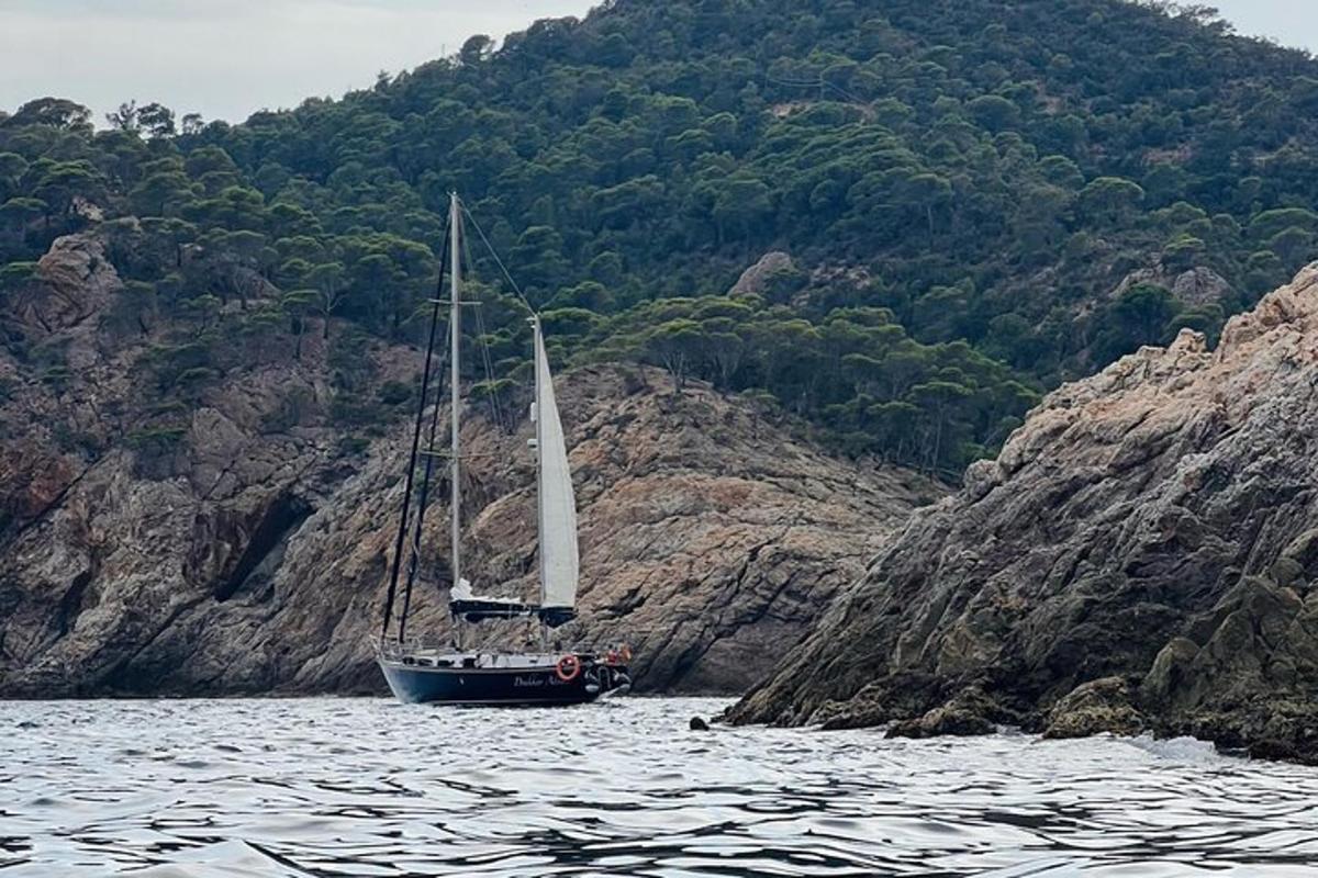 una barca a vela sull'acqua vicino a una montagna