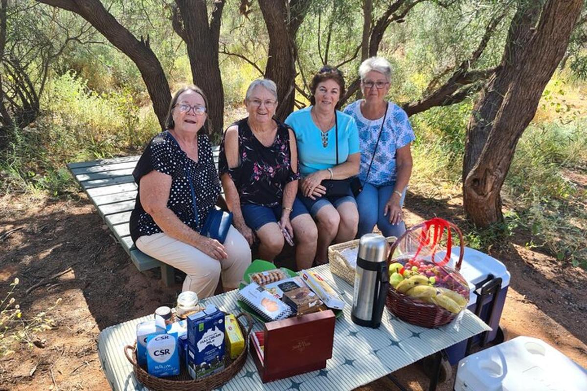 a group of four women sitting on a picnic table