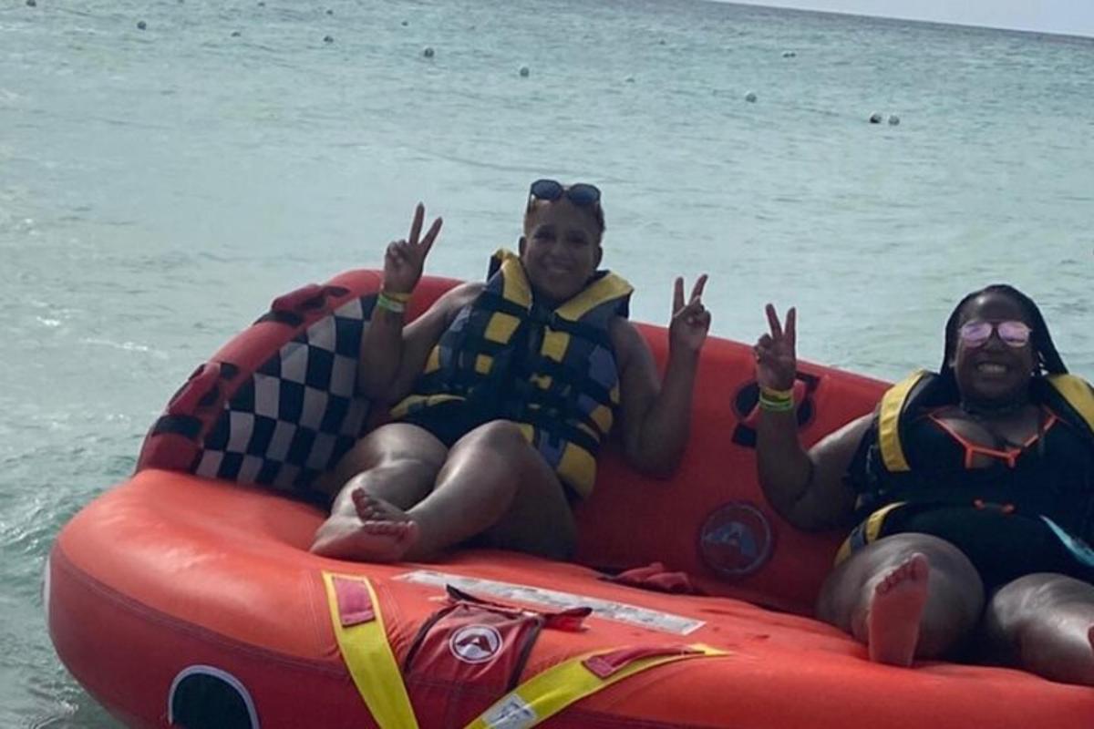 trois personnes portant des gilets de sauvetage allongées sur un radeau anlatable dans l'eau