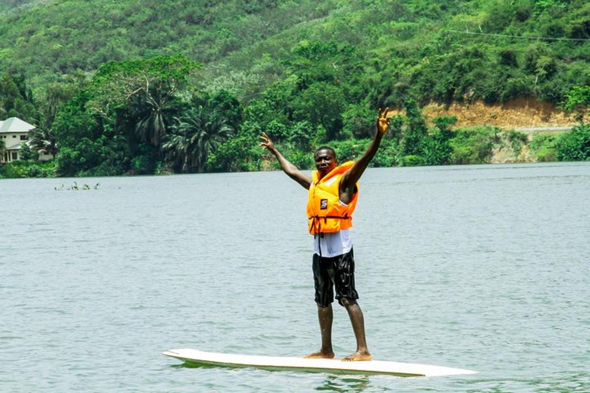 ein Mann in einer orangefarbenen Weste auf einem Surfbrett im Wasser