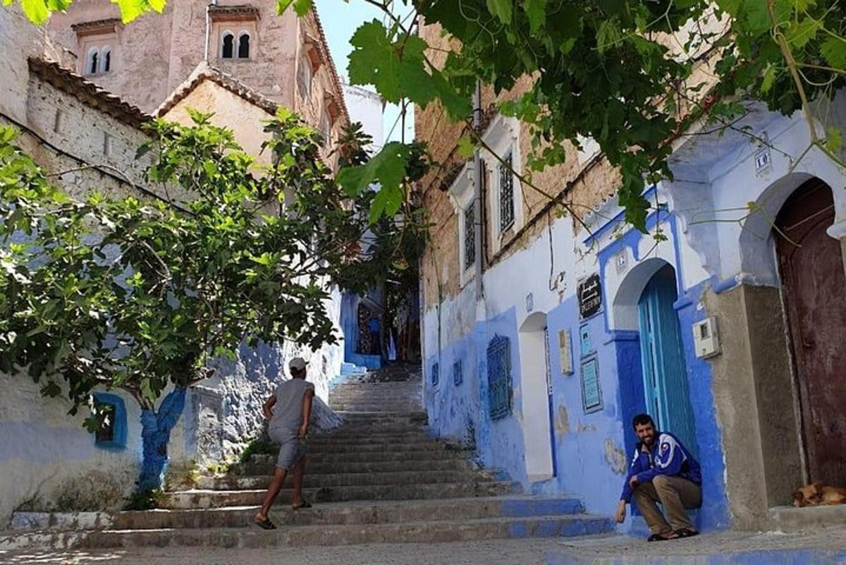 zwei Männer gehen eine Gasse mit blauen Gebäuden entlang
