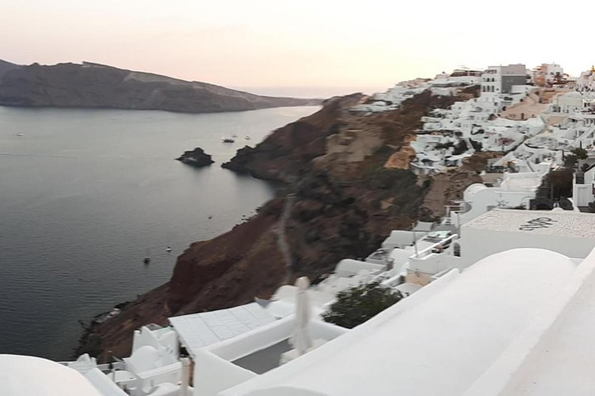 a group of white buildings on a cliff next to the water