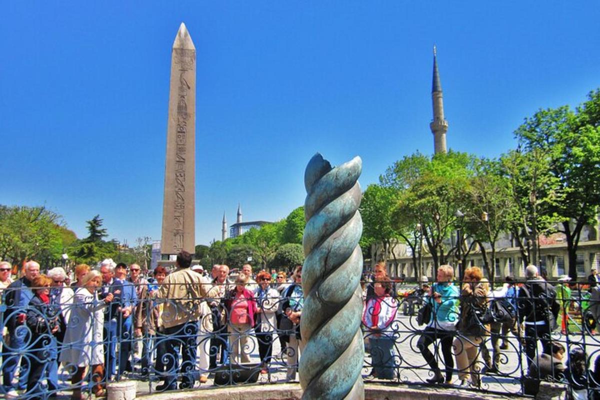 una folla di persone in piedi dietro una recinzione vicino a una statua