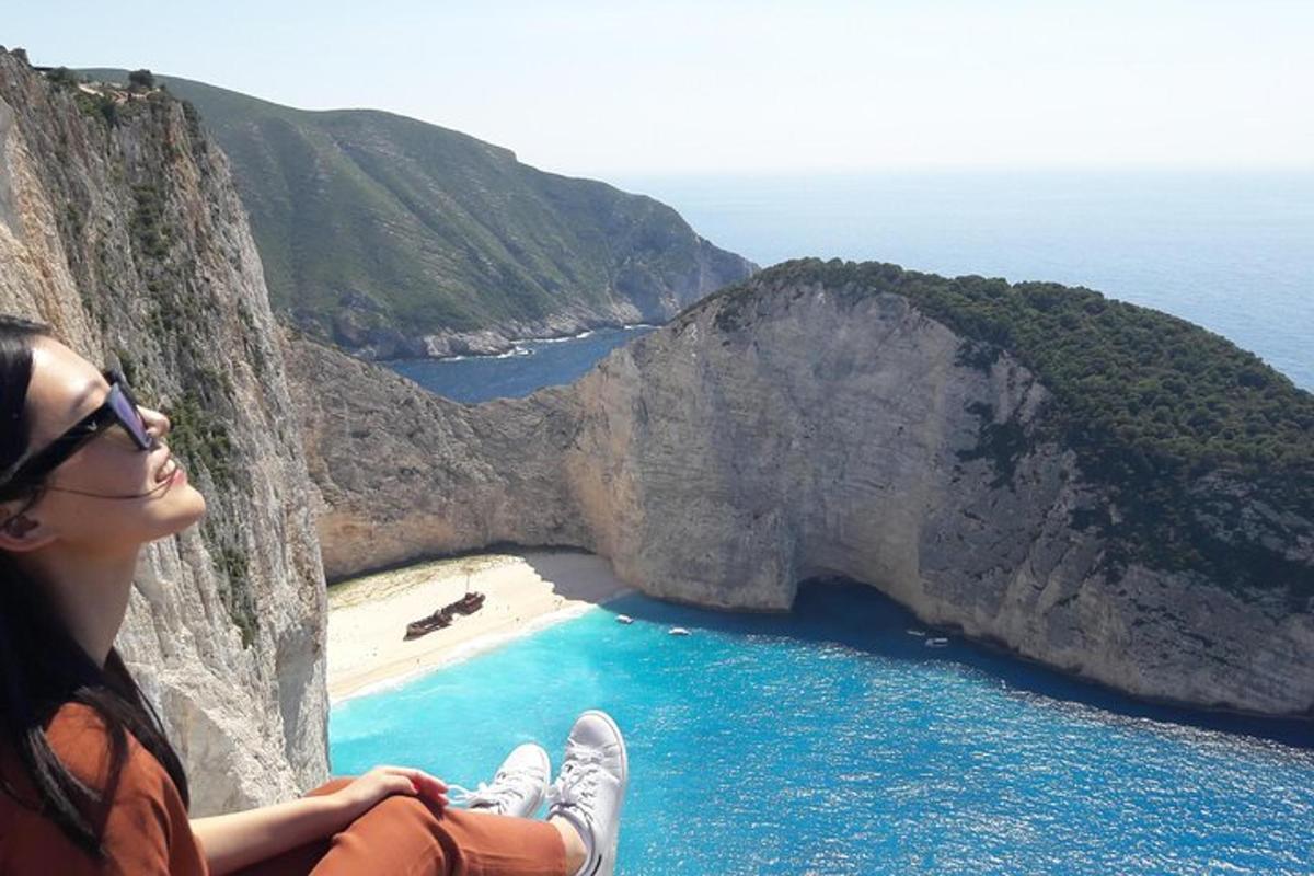 a woman sitting on a cliff overlooking a beach
