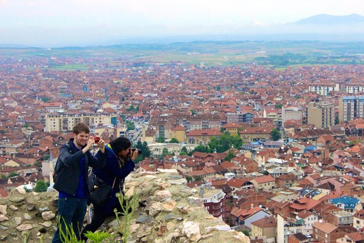 Dos hombres tomando fotografías de una ciudad desde una montaña