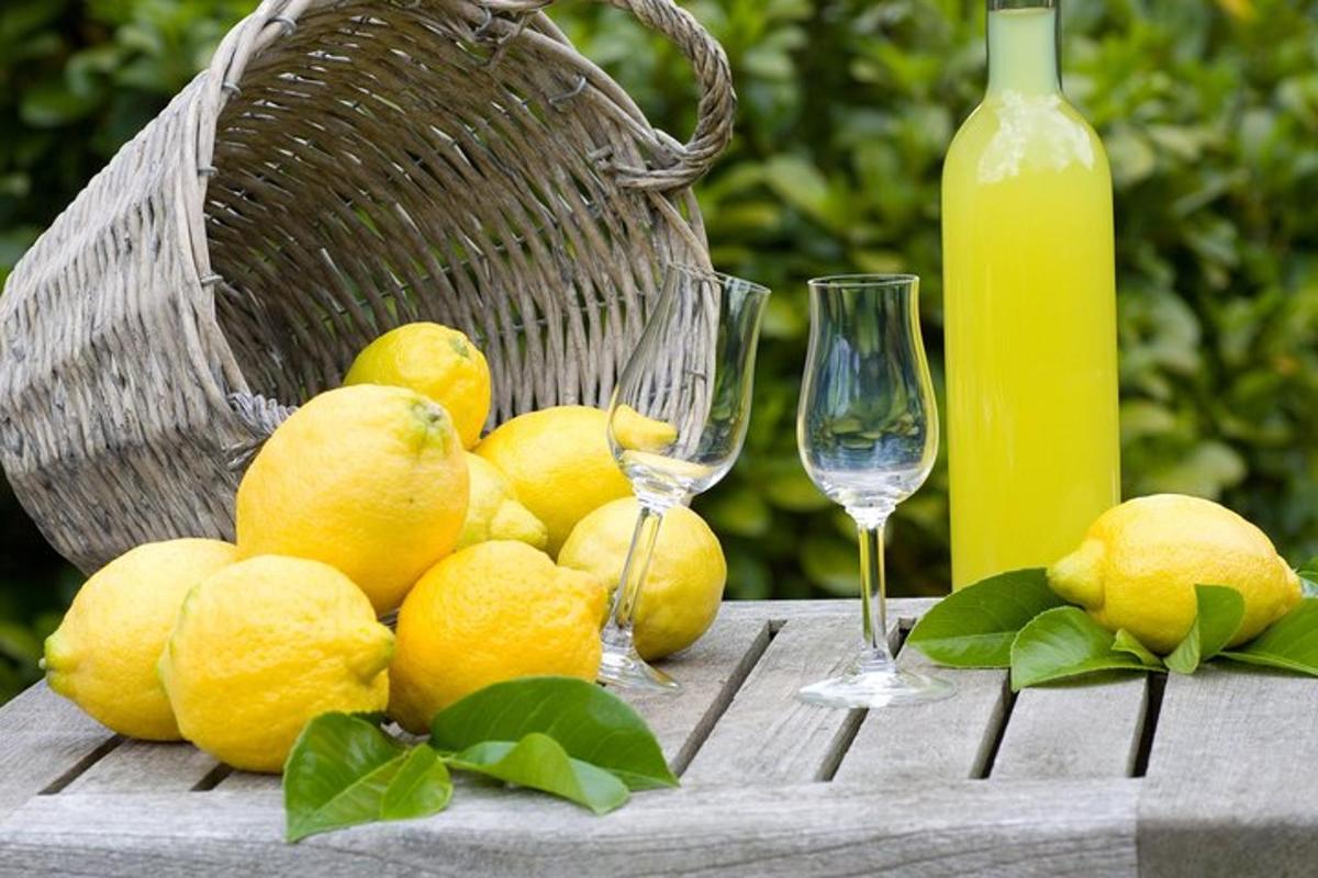 a bunch of lemons on a table with a basket and glasses