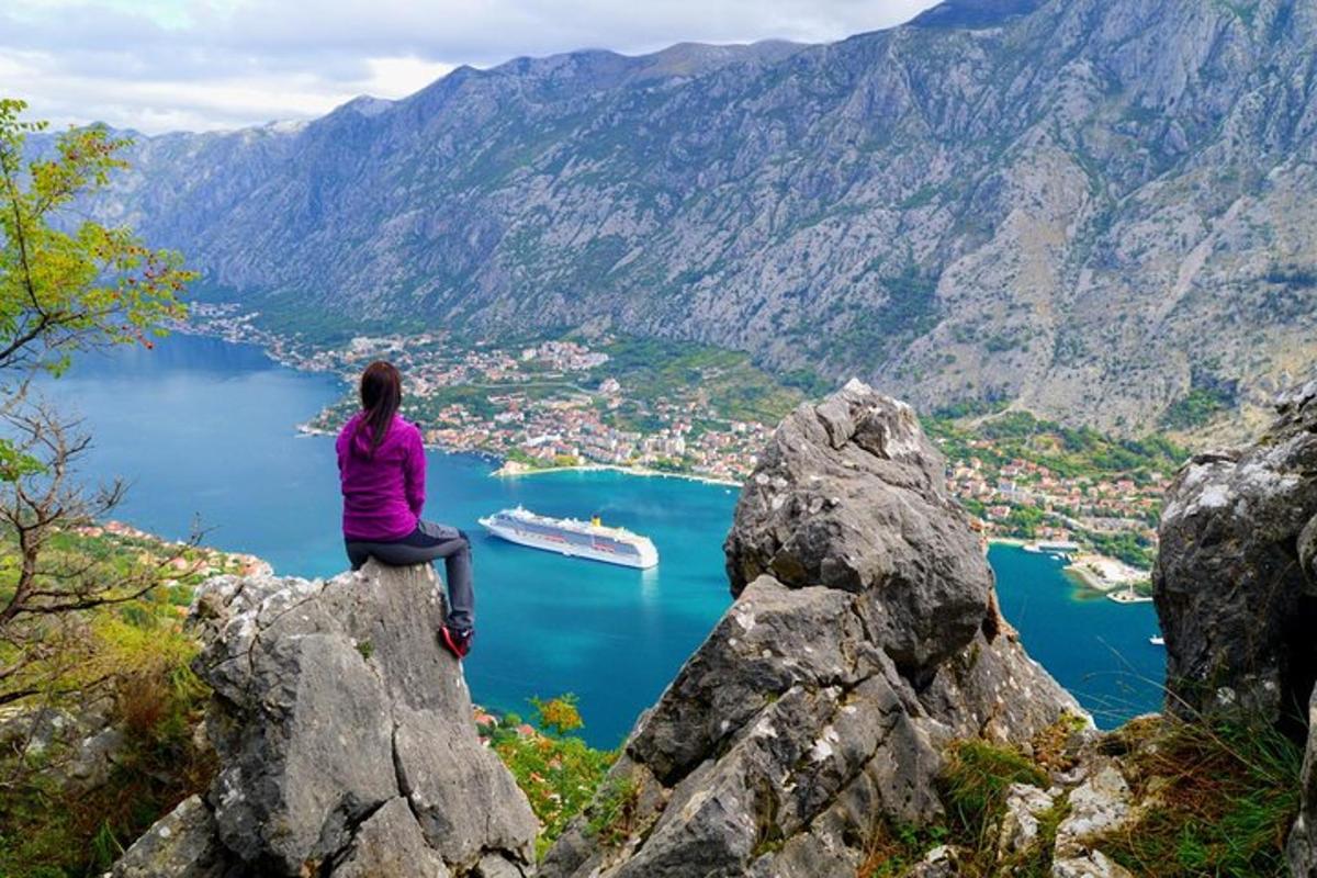kona situr á steini og horfir yfir vatn